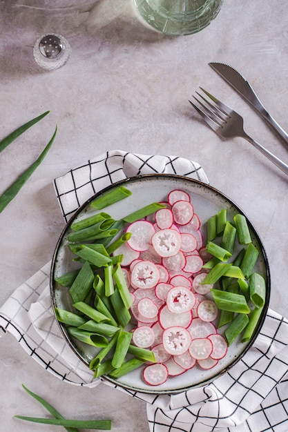 Lente zelfgemaakte radijs en bieslook salade op een bord op het tafelblad en verticale weergave