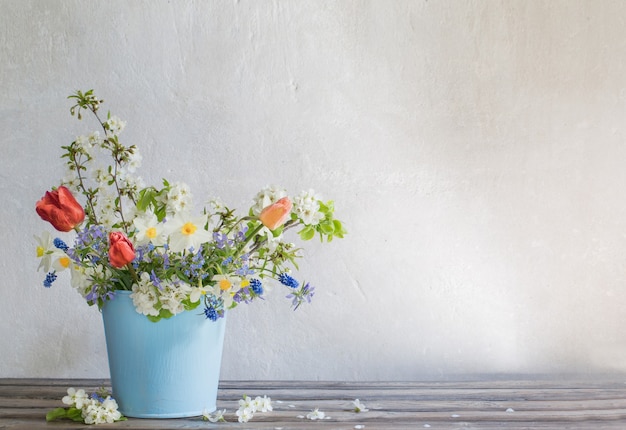 Lentebloemen in blauwe emmer op witte achtergrond