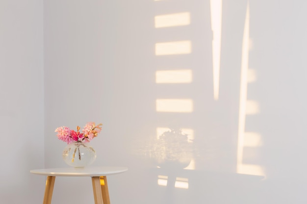 Lentebloemen in glazen vaas op witte achtergrond muur in zonlicht