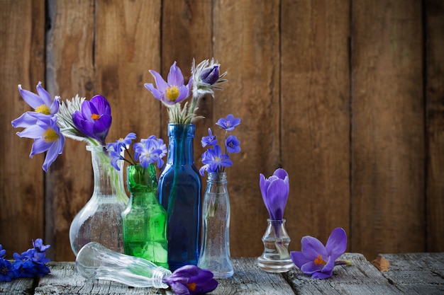 Lentebloemen in glazen vaten op een houten tafel