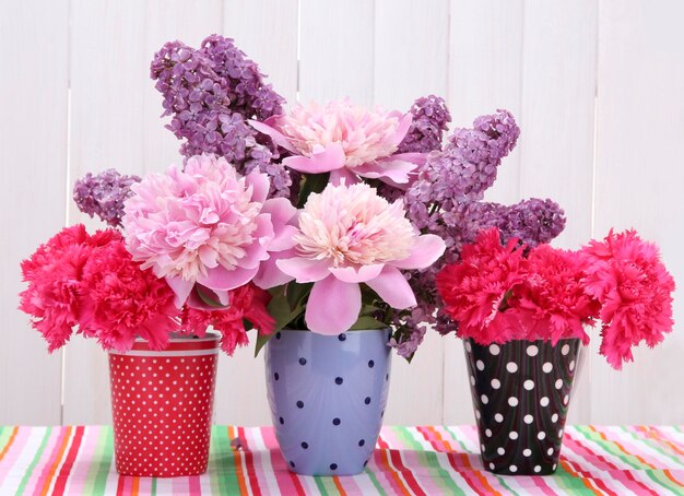 Lentebloemen in kopjes op tafel op witte houten achtergrond