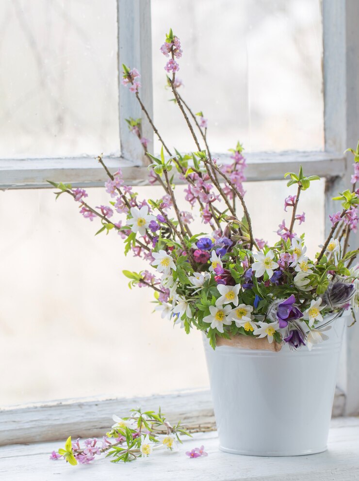 Lentebloemen in witte emmer op oude witte vensterbank