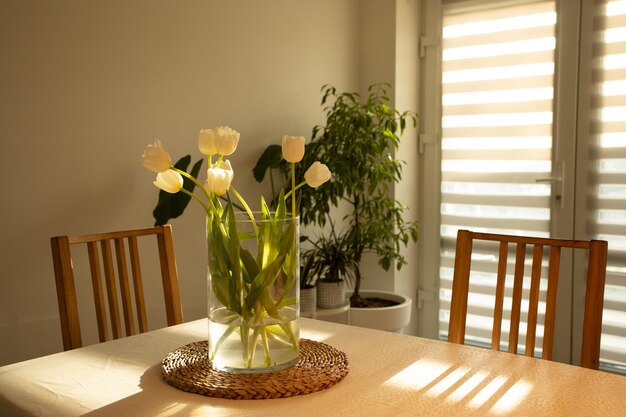 Lentebloemen witte tulpen in glazen vaas op houten tafel