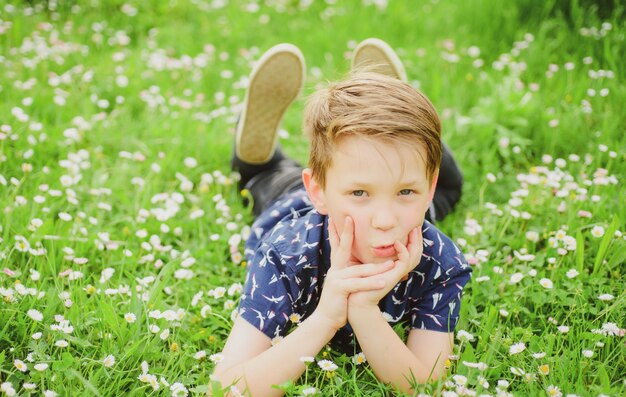 Lentejongen rustend op gras Schattige jongen op veldbloem Dromend kind