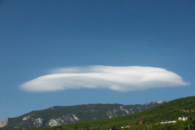 Lenticular cloud over a mountain range, mountains, in the summer in the morning hours.