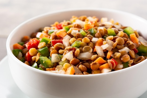 Lentil salad with peppersonion and carrot in a bowl on wooden table