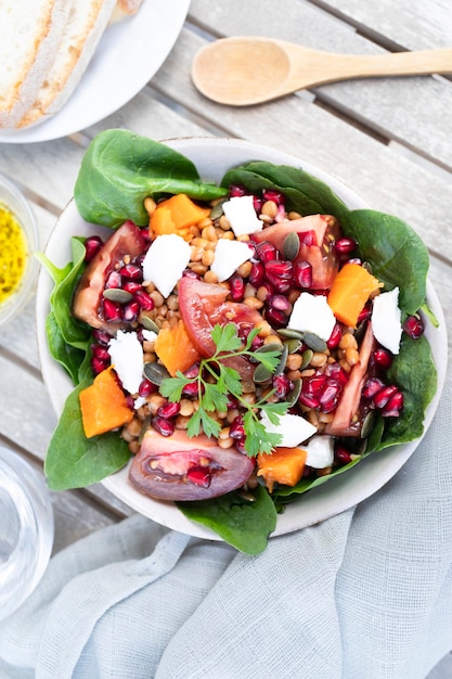 Lentil salad with pumpkin tomatoes pomegranate seeds spinach and goat cheese