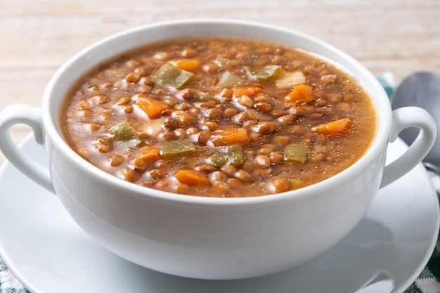 Lentil soup with vegetables in bowl on wooden table