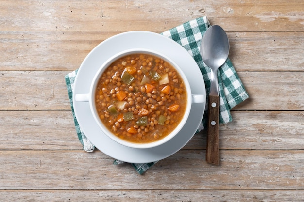 Lentil soup with vegetables in bowl on wooden table