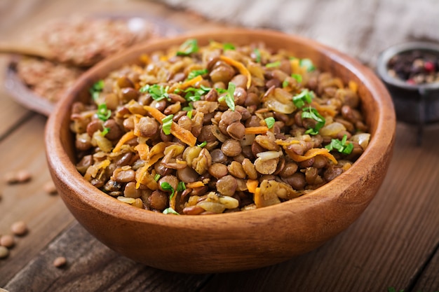 Lentil with carrot and onion in wooden bowl