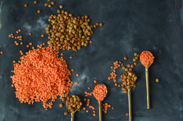 Lentils red and green on a dark old rustic table, vintage spoons. Healthy eating concept.