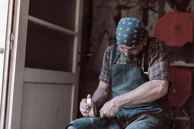 Lepel ambachtelijke meester in zijn atelier met handgemaakte houten producten en gereedschappen werken. Hoge kwaliteit foto