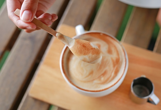 Lepel hete latte koffie op houten tafel.