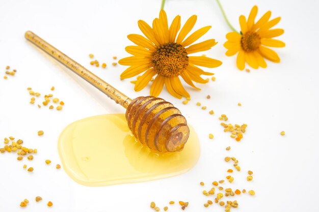 Lepel met verse honing en stuifmeel gemorst op een witte achtergrond. biologisch vitaminevoer