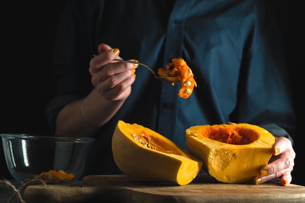 Lepel met zaden in een handpompoenhelften op een tafel op een blauwe achtergrond