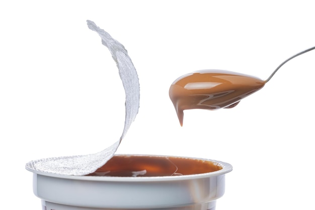 Lepel schept dulce de leche uit een traditionele zoete pot uit Argentinië geïsoleerd op een witte achtergrond