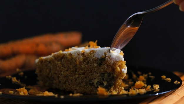 Lepel snijden van een stukje Cinnamon Carrot Cake op donkere achtergrond Darkfood