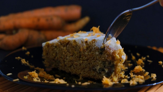 Lepel snijden van een stukje Cinnamon Carrot Cake op donkere achtergrond Darkfood