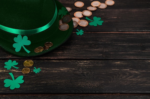 Leprechaun hat and shamrock clover leaves on brown wooden background Happy St Patricks Day