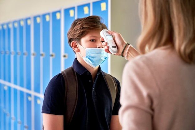 Leraar controleert de temperatuur van de studenten