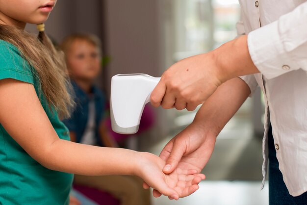 Leraar controleert de temperatuur van haar studenten voor de klas