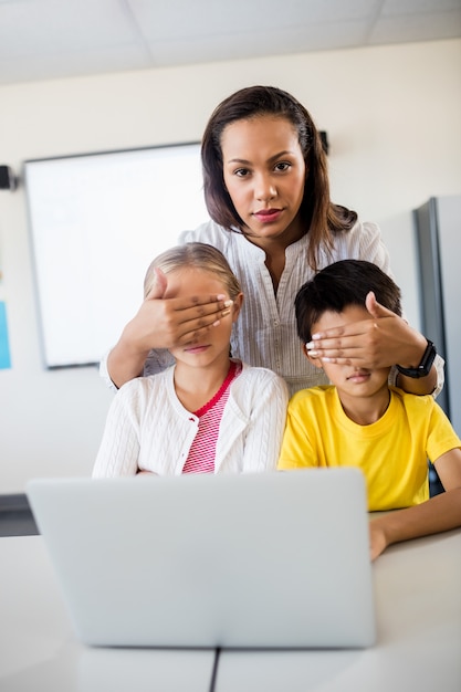 Leraar die leerlingenogen voor computer behandelt en camera bekijkt