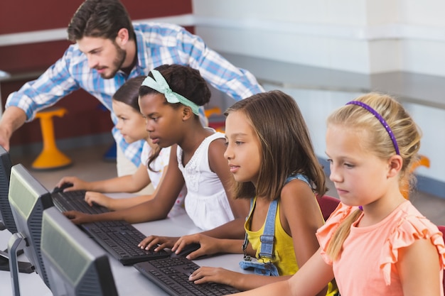 Leraar die schoolmeisjes bijstaan in het leren van computer