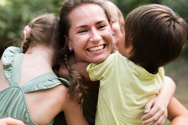 Foto leraar en kinderen knuffelen buitenshuis close-up