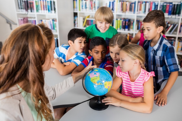 Leraar en leerlingen kijken naar een wereldbol