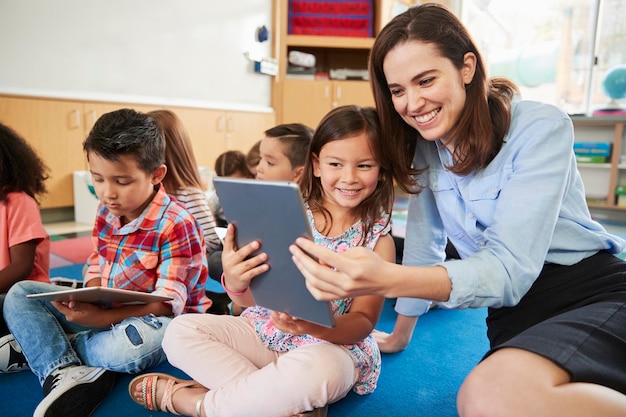 Leraar en meisje in de basisschool gebruiken tabletcomputers