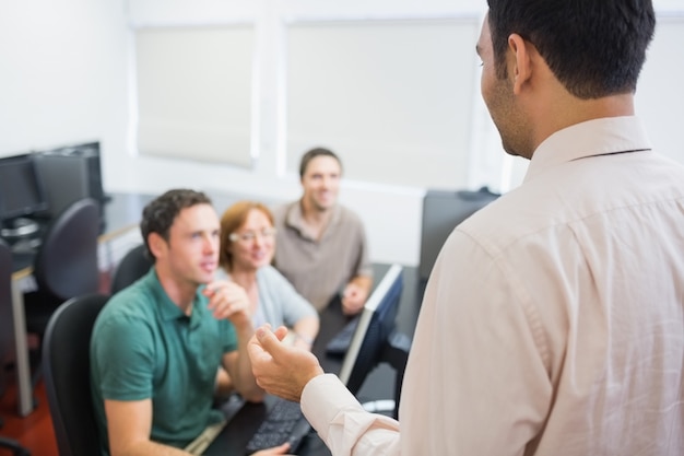 Leraar en volwassen studenten in computerlokaal