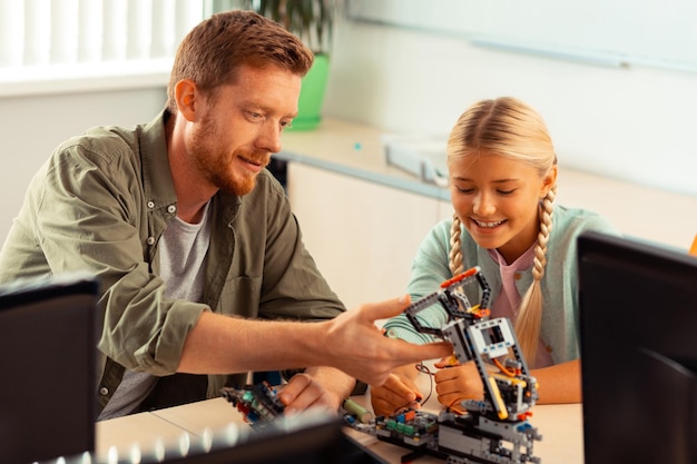 Leraar evalueert de robot gemaakt door het schoolmeisje