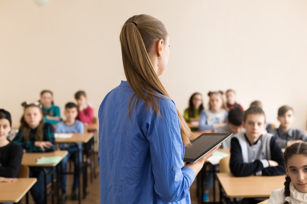 Leraar haar studenten een vraag stellen op de basisschool met tabletcomputer