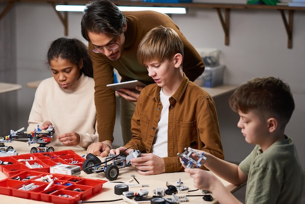 Leraar helpt kinderen in roboticaklas