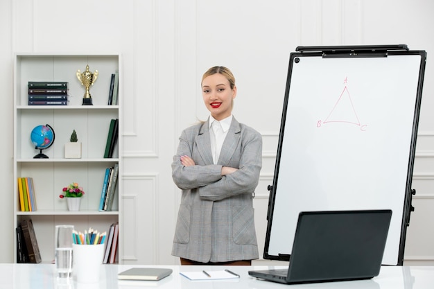 Leraar jonge schattige instructeur in pak in klas met laptop en whiteboard die handen kruisen