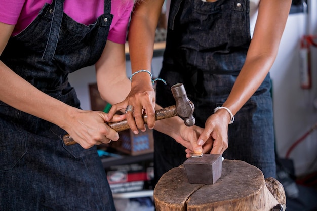 Leraar juwelier en student maken sieraden in werkplaats