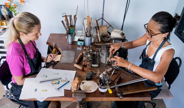 Leraar juwelier en student maken sieraden in werkplaats