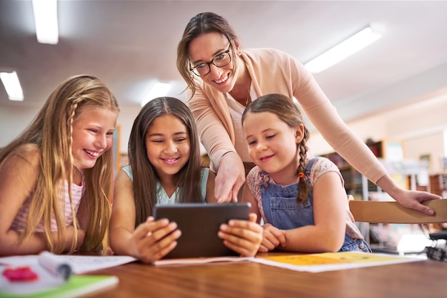 Leraar kinderen en helpen met tablet voor onderwijs e-learning en wiskunde spel voor getallen oplossen vaardigheid School opvoeder en gelukkige studenten in de basisschool voor kennis vermenigvuldiging of studeren app