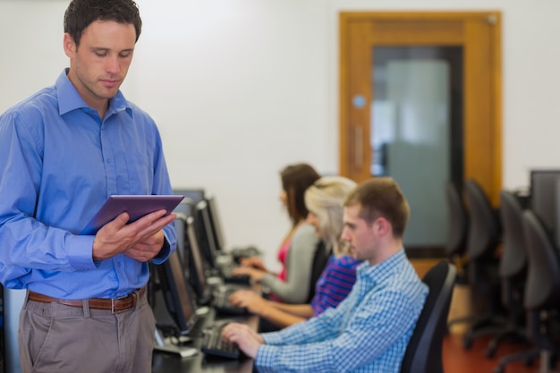 Leraar met studenten die computers in computerzaal gebruiken