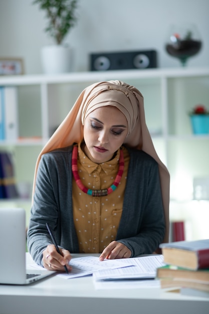 Leraar voelt zich druk. Jonge hardwerkende leraar die hijab draagt, voelt zich druk tijdens het corrigeren van de tests