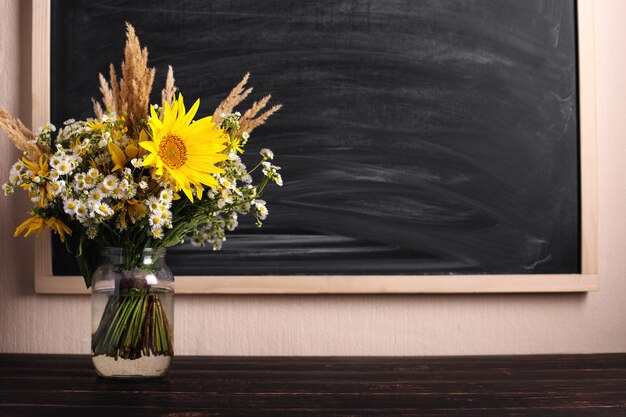 Leraren dag. Zwart bord en verse wilde bloemen in vaas.