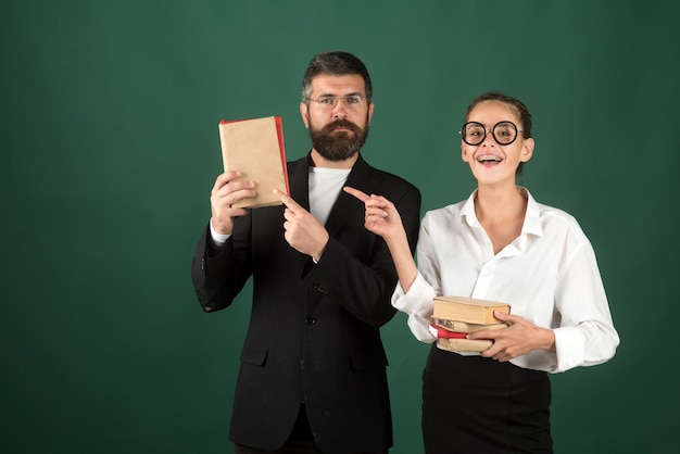 Lerarendag met man en jonge vrouw die met de vinger wijzen op boeken die productkopieerruimte presenteren