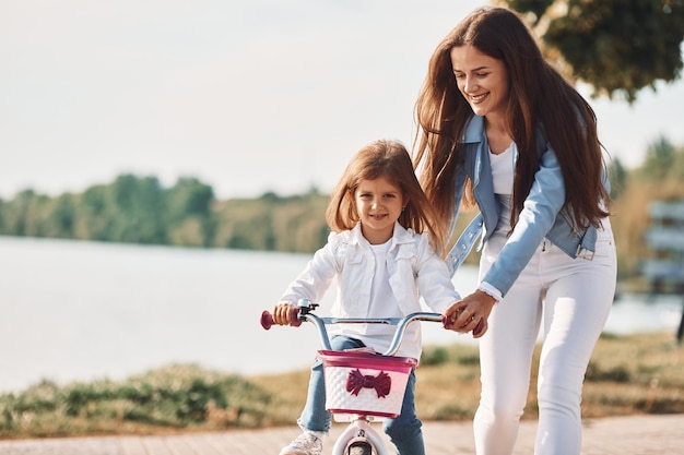 Leren autorijden Moeder met haar jonge dochter is samen op de fiets buiten