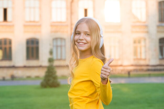 Leren op afstand. gelukkig klein meisje dat een koptelefoon draagt. stereogeluid. goede verhalen luisteren. zelf onderwijs. koptelefoon met draadloze technologie. klein kind luisteren naar muziek moderne oortelefoons.