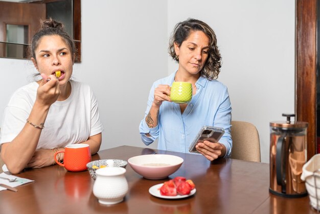 レズビアンのカップルが朝食をとり、そのうちの 1 人が携帯電話を見ている