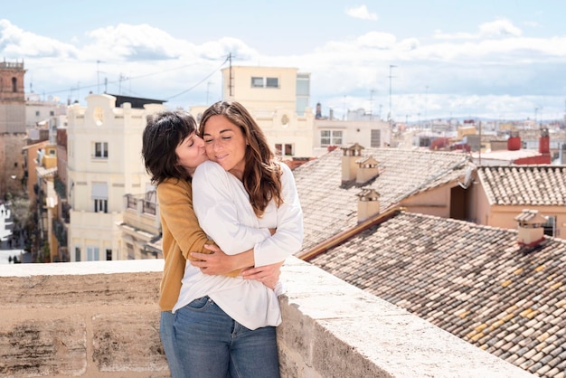 Lesbian couple hugging on rooftop with city view