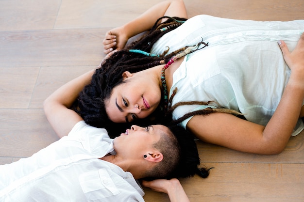 Lesbian couple lying on wooden floor and smiling