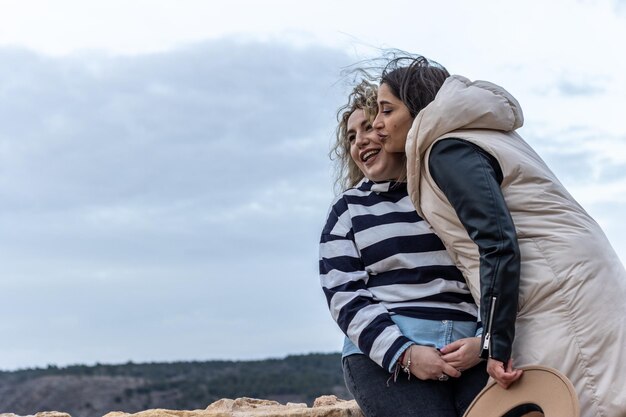 A lesbian couple spending the day together in nature with a hill in the background on a cloudy day