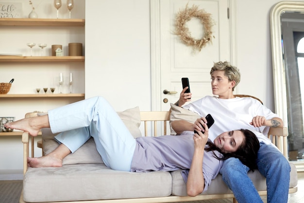 Lesbian couple using smartphones on sofa