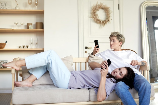 Photo lesbian couple using smartphones on sofa